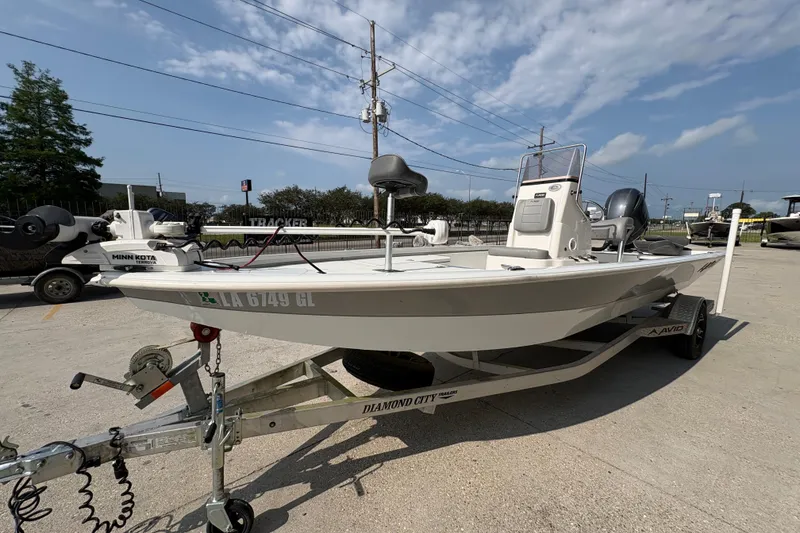 Slide: The Image of 2021 Avid 21 FS boat on trailer, featuring Minn Kota trolling motor, parked outdoors. - 8