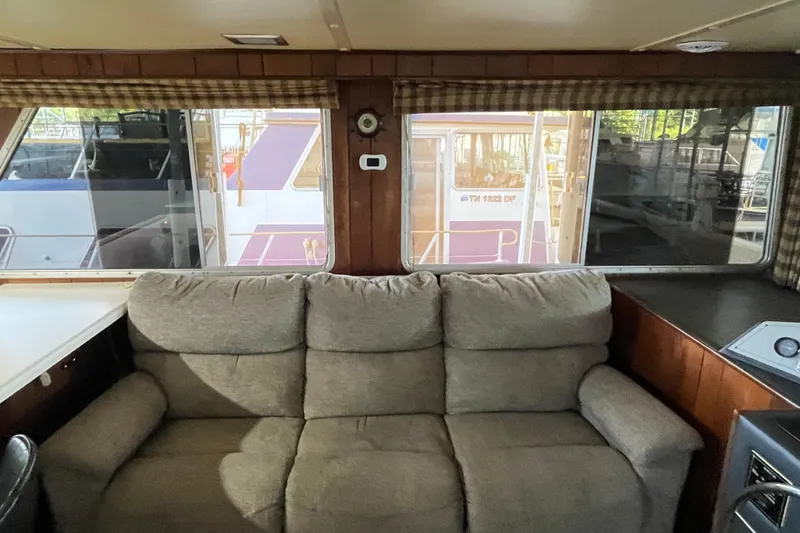 Slide: The Image of Interior of a 1990 Gibson 44 boat with a cozy sofa and large windows. - 11