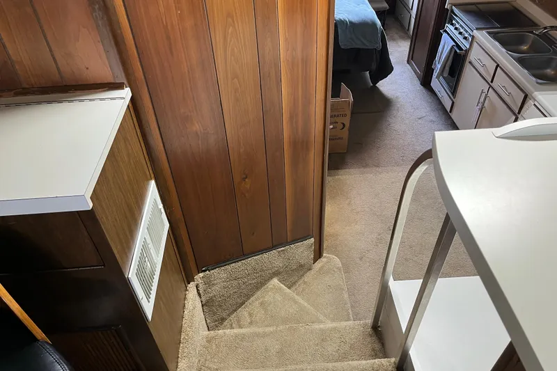 Slide: The Image of Interior of a 1990 Gibson 44 boat with stairs, kitchen, and wood paneling. - 13