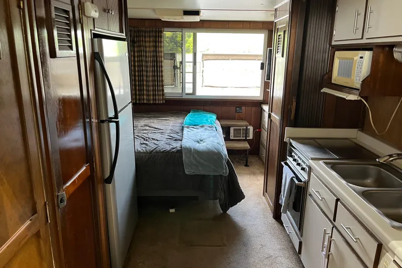 Slide: The Image of Compact 1990 Gibson 44 interior with bed, kitchenette, and appliances. Cozy and functional space. - 16