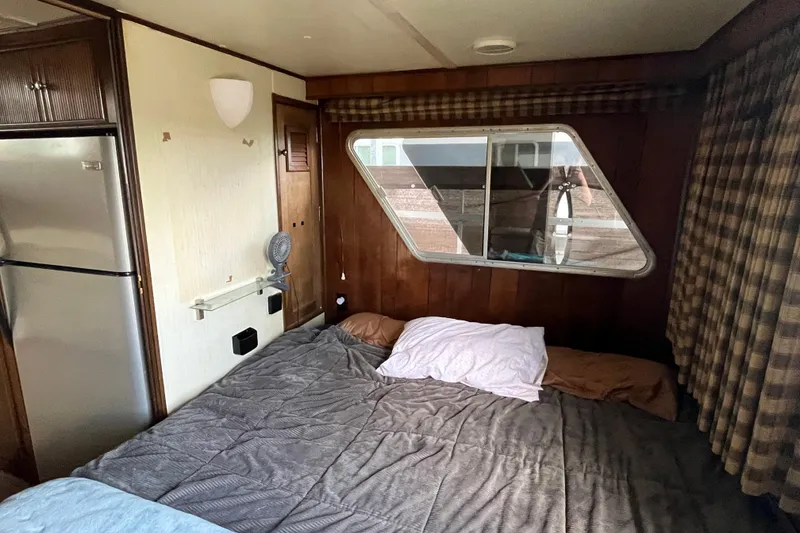 Slide: The Image of Cozy bedroom in 1990 Gibson 44 boat with bed, window, and fridge. - 17