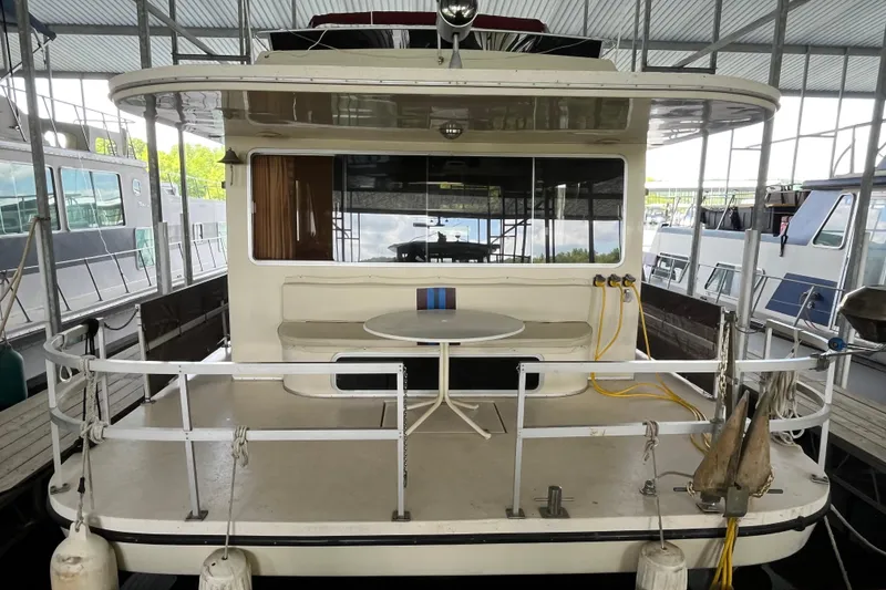 Slide: The Image of 1990 Gibson 44 boat docked, featuring a spacious rear deck with seating and table. - 2