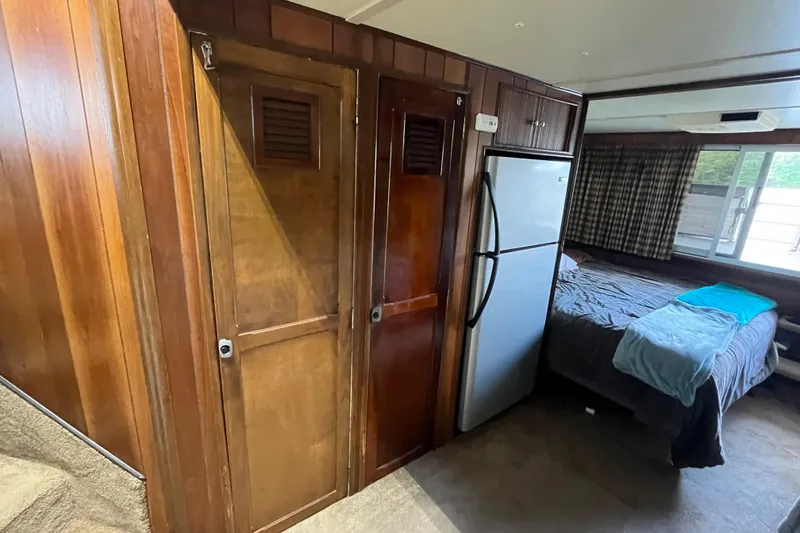 Slide: The Image of Interior of a 1990 Gibson 44 boat with wood paneling, fridge, and cozy bedroom. - 22