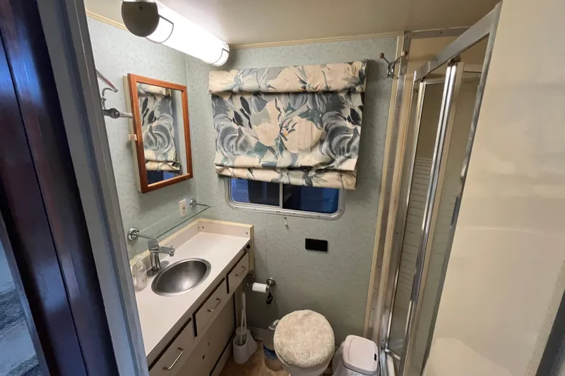 Slide: The Image of Compact bathroom in a 1990 Gibson 44, featuring sink, mirror, and floral curtain. - 23