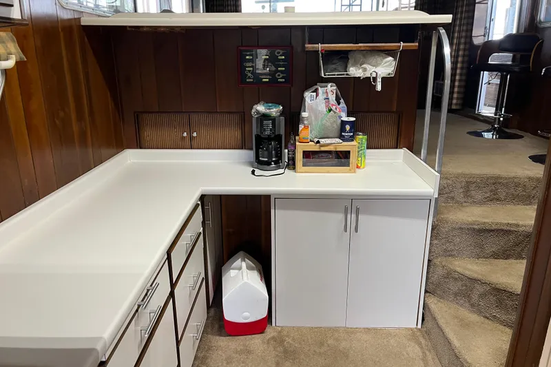 Slide: The Image of Kitchen area in a 1990 Gibson 44 boat with white cabinets and wood paneling. - 25