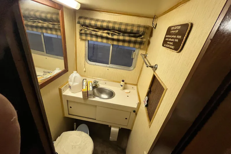 Slide: The Image of Compact bathroom in a 1990 Gibson 44 boat with sink, mirror, and window. - 29