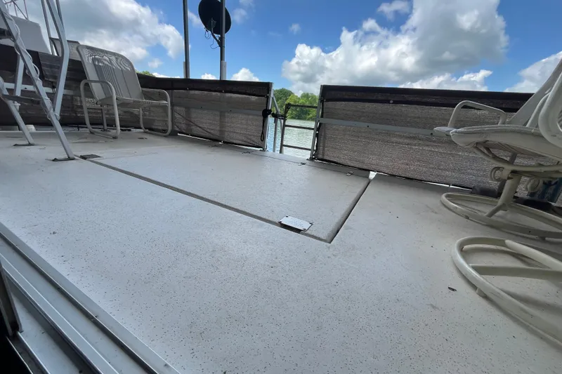 Slide: The Image of Deck of a 1990 Gibson 44 boat with chairs, railing, and a scenic water view. - 33