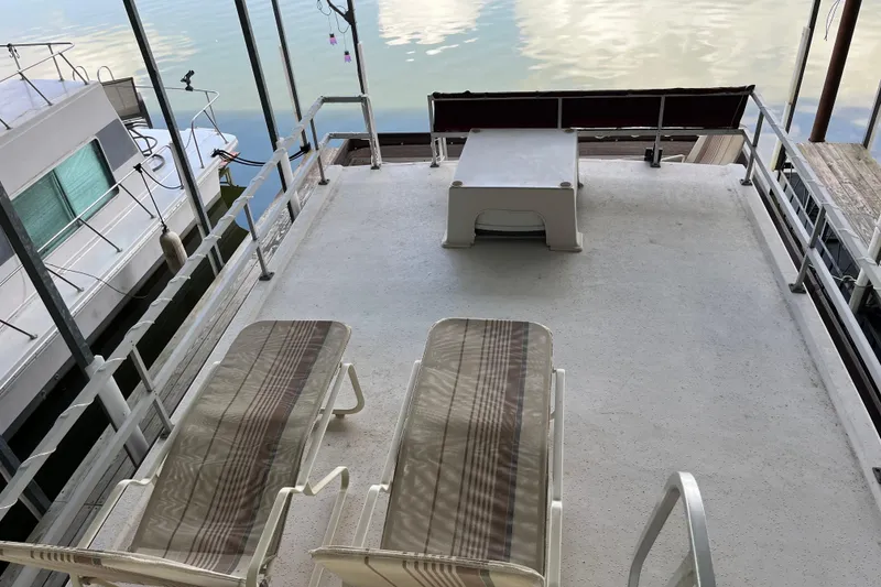 Slide: The Image of Deck of a 1990 Gibson 44 houseboat with lounge chairs and a table by the water. - 40