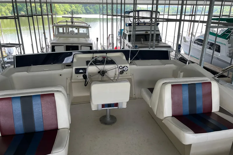 Slide: The Image of 1990 Gibson 44 boat interior with striped seating and steering wheel, docked at marina. - 41