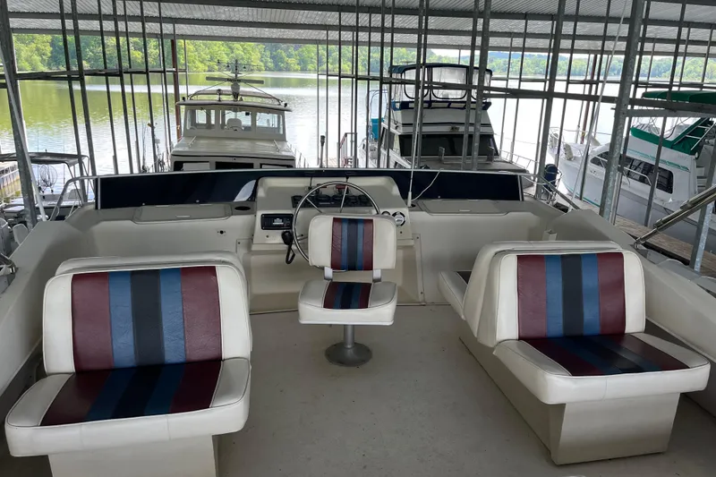 Slide: The Image of 1990 Gibson 44 boat interior with striped seating, docked in a covered marina. - 44