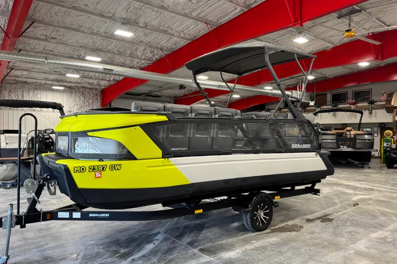 The Image of 2023 Sea-Doo Switch Cruise 21 pontoon boat in a showroom with vibrant yellow accents. - 7