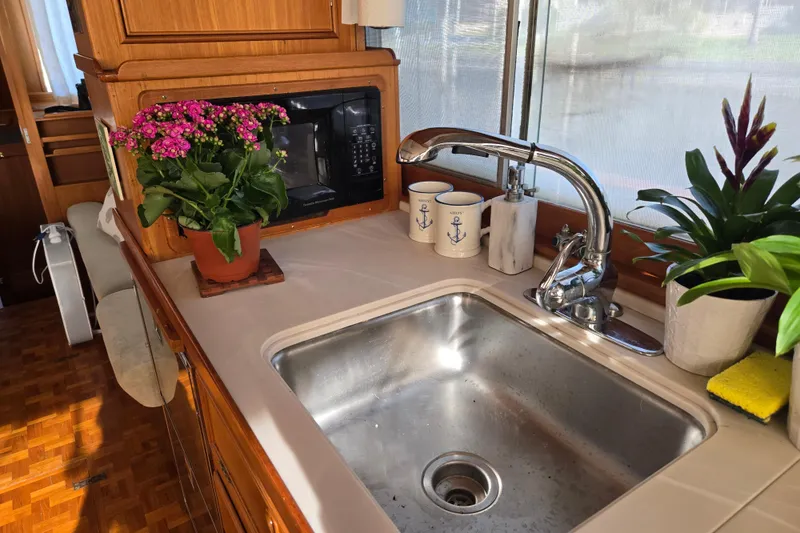 Slide: The Image of Kitchen sink area on a 1992 Grand Banks 46 Classic yacht with plants and nautical mugs. - 25