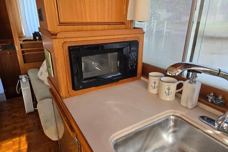 Slide: The Image of 1992 Grand Banks 46 Classic yacht kitchen with microwave, sink, and nautical-themed mugs. - 26