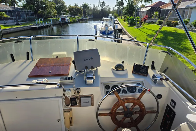 Slide: The Image of Helm of 1992 Grand Banks 46 Classic yacht with Garmin navigation, overlooking a serene canal. - 67