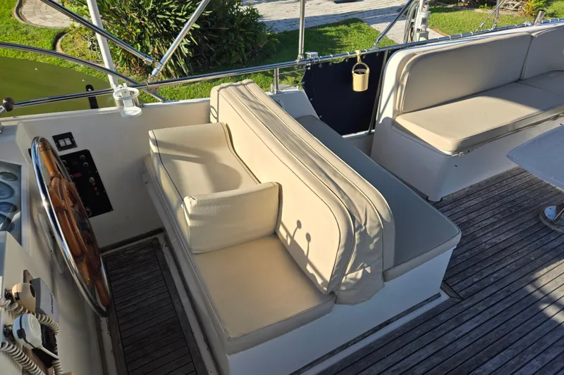 Slide: The Image of 1992 Grand Banks 46 Classic yacht cockpit with cushioned seating and wooden steering wheel. - 74
