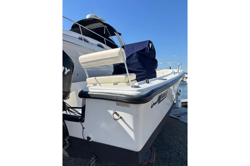 Slide: The Image of 2006 Mako 171 Center Console boat docked, featuring a covered seating area and outboard motor. - 14