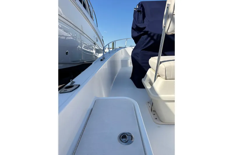 Slide: The Image of 2006 Mako 171 Center Console boat deck with seating and railing, docked beside another vessel. - 15