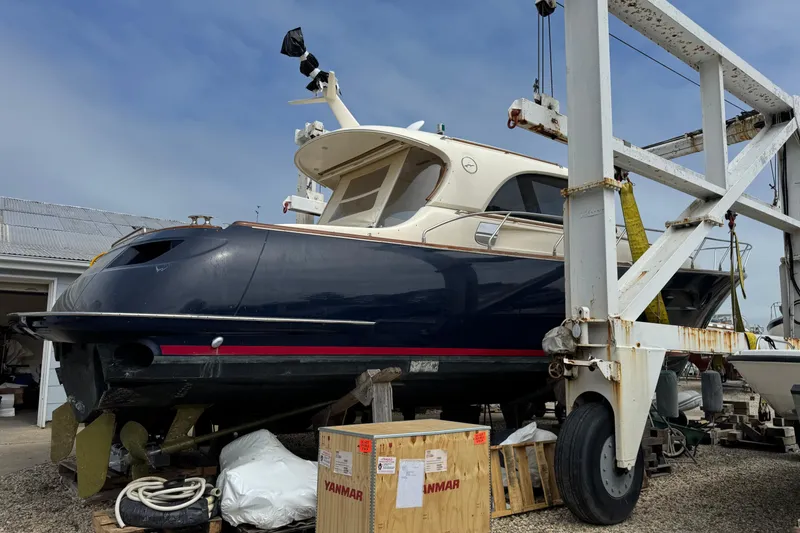 Slide: The Image of 2009 Mochi Craft 44 Dolphin yacht on dry dock, surrounded by equipment and crates. - 7
