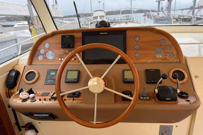 Slide: The Image of 2009 Mochi Craft 44 Dolphin yacht helm with wooden steering wheel and navigation instruments. - 9