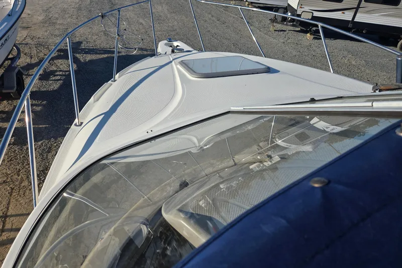 Slide: The Image of 2001 Maxum 2400 SCR boat on gravel, showcasing deck and railing details. - 32