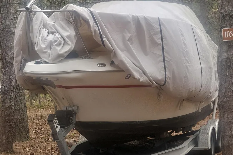 Slide: The Image of 2001 Maxum 2400 SCR boat on trailer with American flag, parked near road. - 9