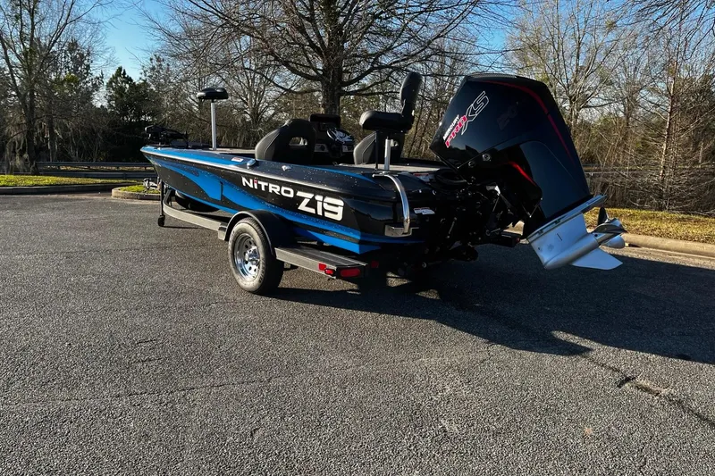 Slide: The Image of 2024 Nitro Z19 boat with powerful engine, parked on asphalt, surrounded by trees. - 3