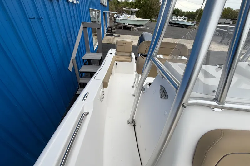 Slide: The Image of 2017 Tidewater 198 CC Adventure boat interior with seating and railing, docked near blue building. - 7
