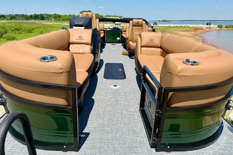 Slide: The Image of Luxurious 2026 Regency 230 DL pontoon boat with tan seating, docked by a scenic lake. - 7