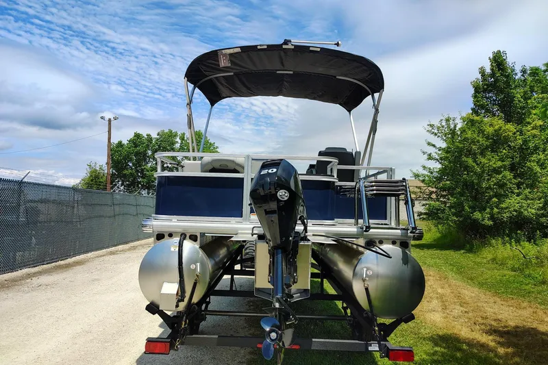 Slide: The Image of 2026 Sun Tracker Bass Buggy 18 DLX pontoon boat with canopy, parked outdoors. - 1
