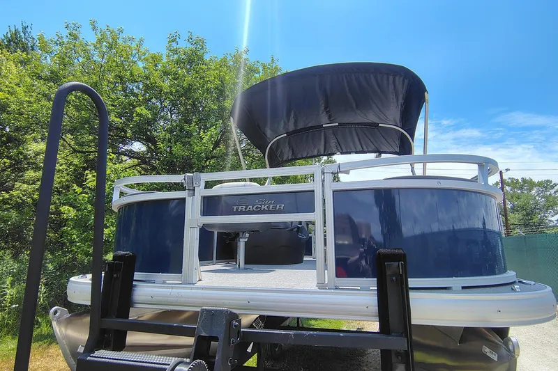 Slide: The Image of 2026 Sun Tracker Bass Buggy 18 DLX pontoon boat with canopy, parked outdoors. - 6