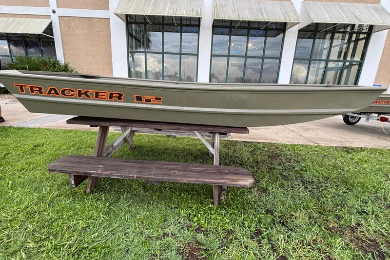The Image of 2026 Tracker Grizzly 12 Jon boat displayed on a wooden table outdoors. - 0