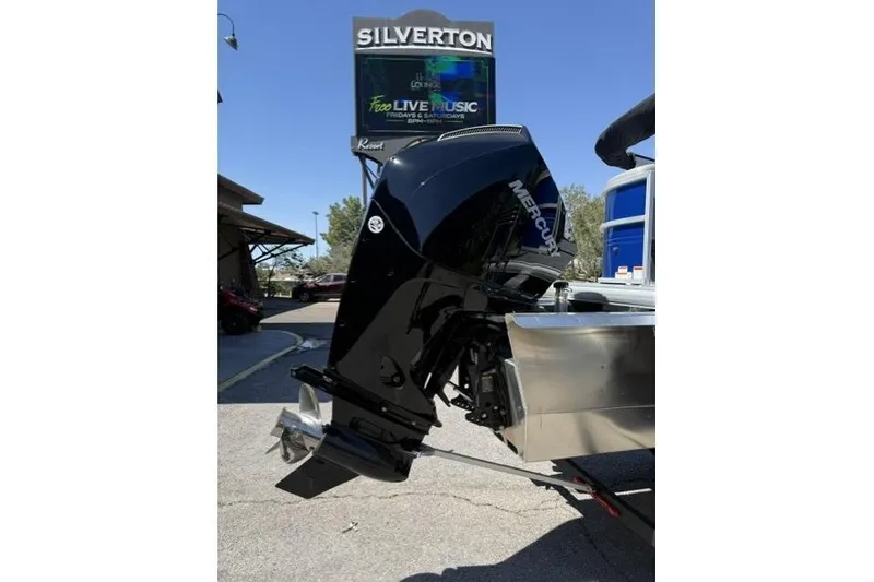 Slide: The Image of 2026 Sun Tracker Party Barge 24 XP3 with Mercury outboard motor, parked near Silverton sign. - 6