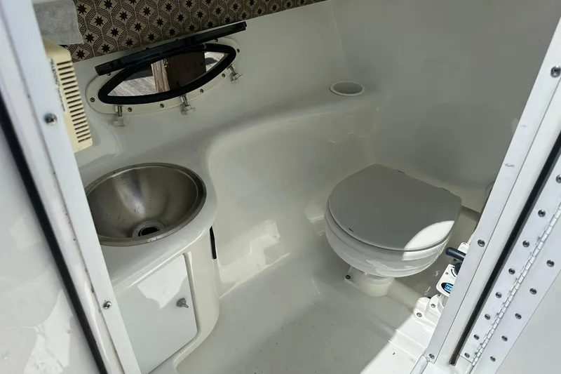 Slide: The Image of 2004 Formula 260 Bowrider boat bathroom with sink and toilet, featuring compact design. - 23