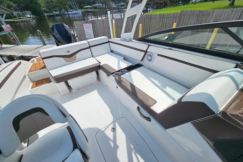Slide: The Image of 2020 Monterey M-225 boat interior with white and brown seating, docked by a lakeside. - 11