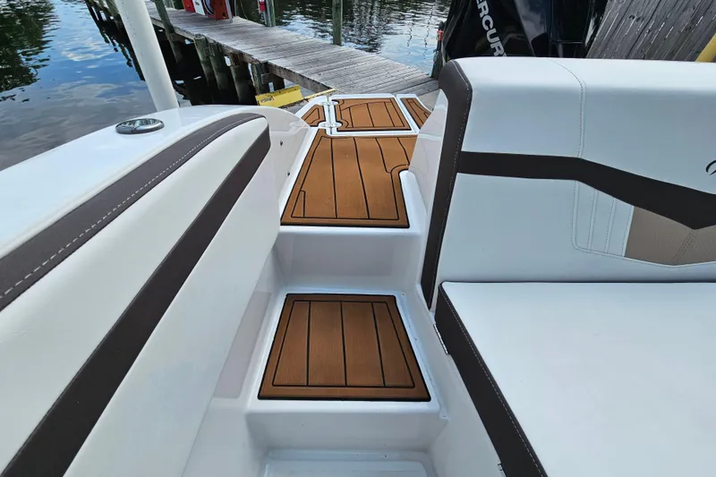Slide: The Image of 2020 Monterey M-225 boat interior with teak-style flooring and white cushioned seating. - 15