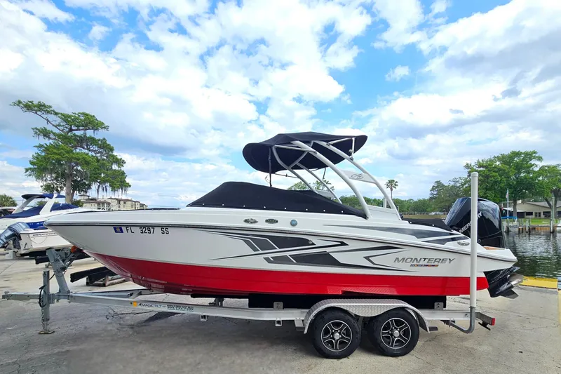 Slide: The Image of 2020 Monterey M-225 boat on trailer, white and red design, parked near water. - 6