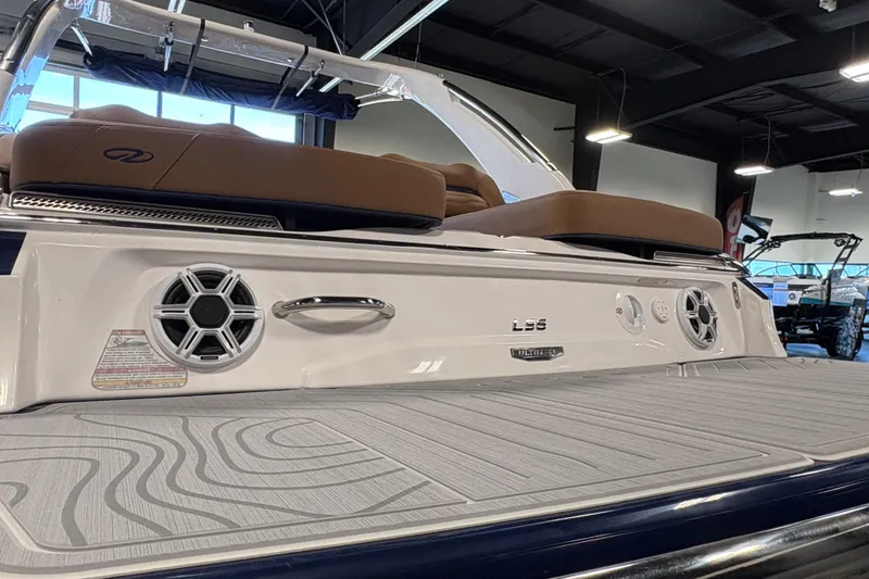 Slide: The Image of 2026 Regal LS6 boat interior with speakers and cushioned seating in a showroom. - 22