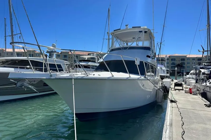 Slide: The Image of 1991 Hatteras 43 Convertible yacht docked in marina under clear blue sky. - 4