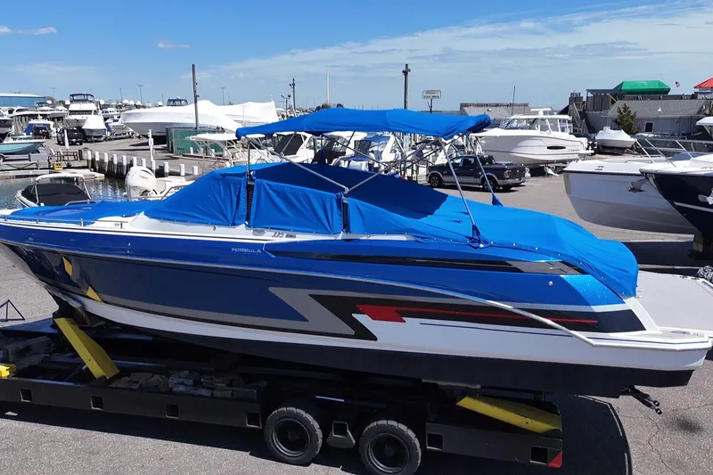 The Image of 2018 Formula 330 Crossover Bowrider I/O boat with blue cover at marina. - 0