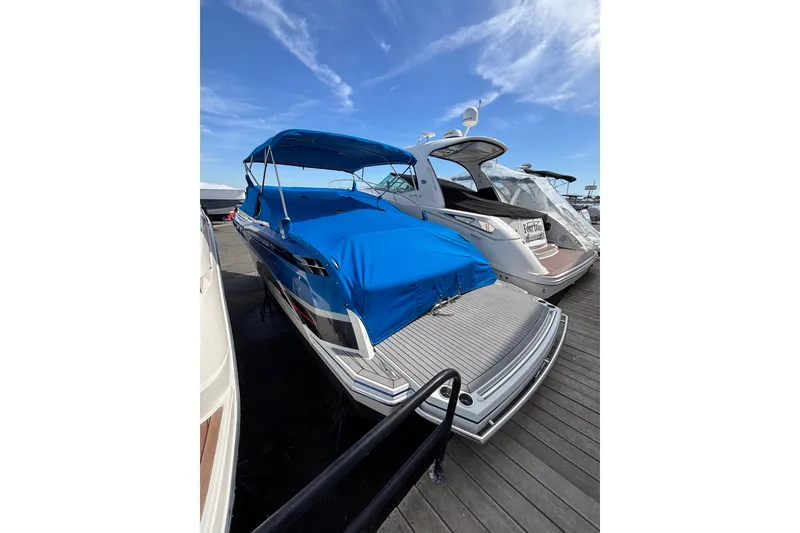 Slide: The Image of 2018 Formula 330 Crossover Bowrider I/O with blue cover docked under clear sky. - 2