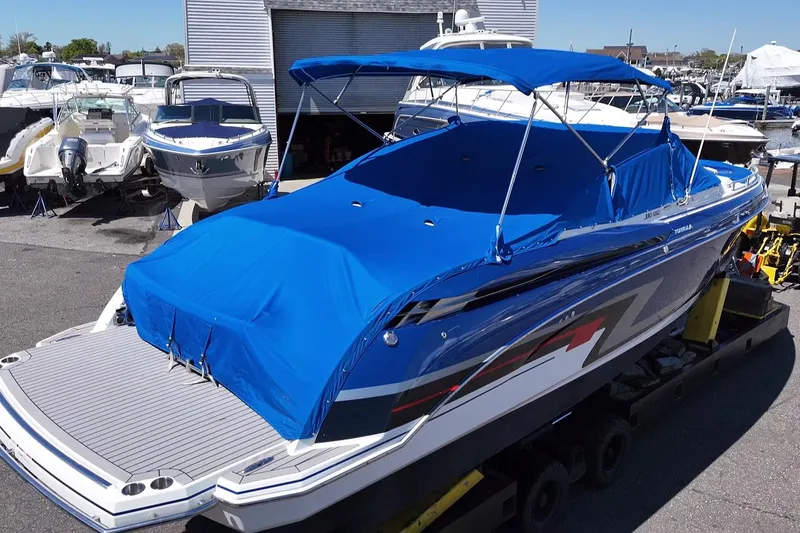 Slide: The Image of 2018 Formula 330 Crossover Bowrider I/O with blue cover in a marina setting. - 24