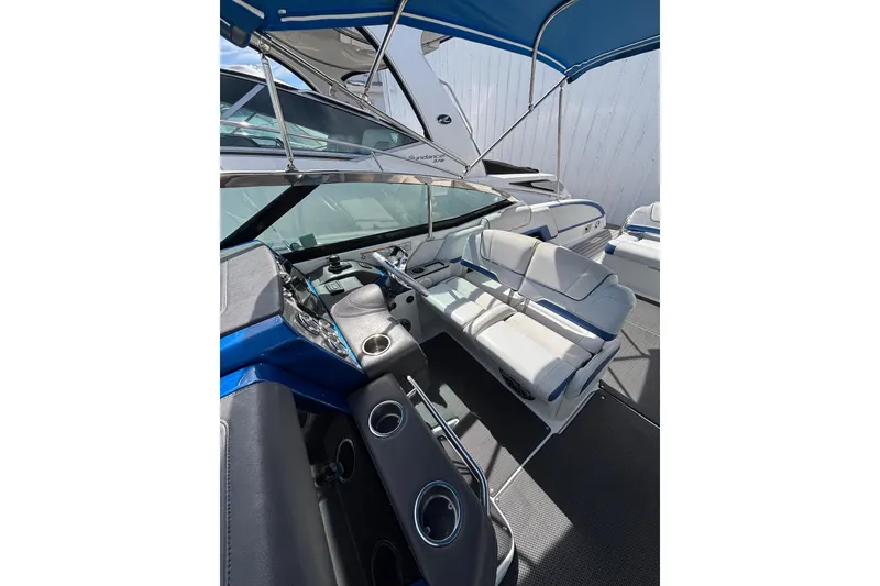 Slide: The Image of 2018 Formula 330 Crossover Bowrider I/O interior with seating and helm under blue canopy. - 7