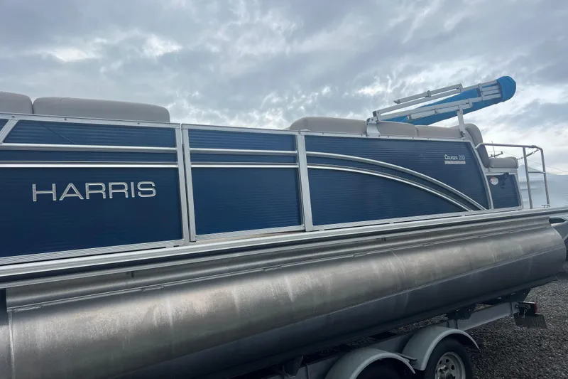 Slide: The Image of 2019 Harris Cruiser 210 pontoon boat with blue siding and silver accents. - 31