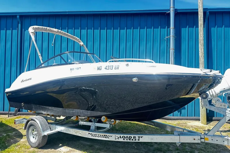 The Image of 2021 Godfrey Hurricane SD191 boat on trailer, parked outdoors by blue building. - 0