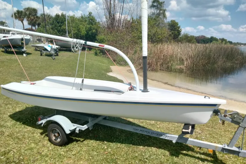 Slide: The Image of 2014 Catalina 12.5 Expo sailboat on trailer by a lakeside, under a clear sky. - 6