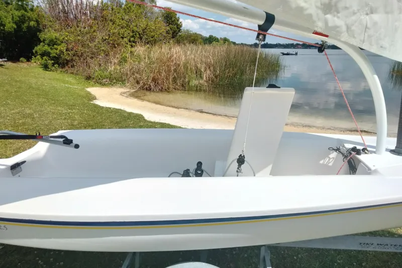 Slide: The Image of 2014 Catalina 12.5 Expo sailboat on grassy shore by a calm lake. - 8