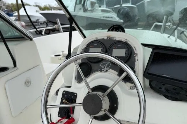 Slide: The Image of Steering wheel and dashboard of a 2001 Sailfish 198 DC boat, featuring gauges and a Garmin device. - 8