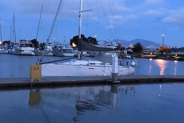 The Image of 2002 Beneteau First 36.7 sailboat docked at a serene marina during twilight. - 2