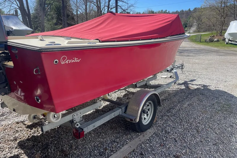 Slide: The Image of 2018 Rossiter 17 Closed Deck boat with red cover on trailer. - 2