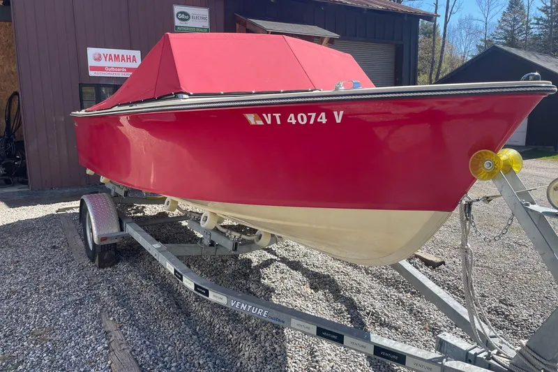 Slide: The Image of Red 2018 Rossiter 17 Closed Deck boat on trailer, parked outside a Yamaha service center. - 3